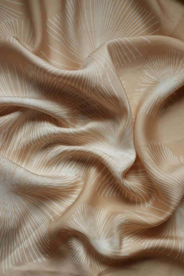 Elegant beige fabric showcasing delicate white botanical designs, perfect for design projects.