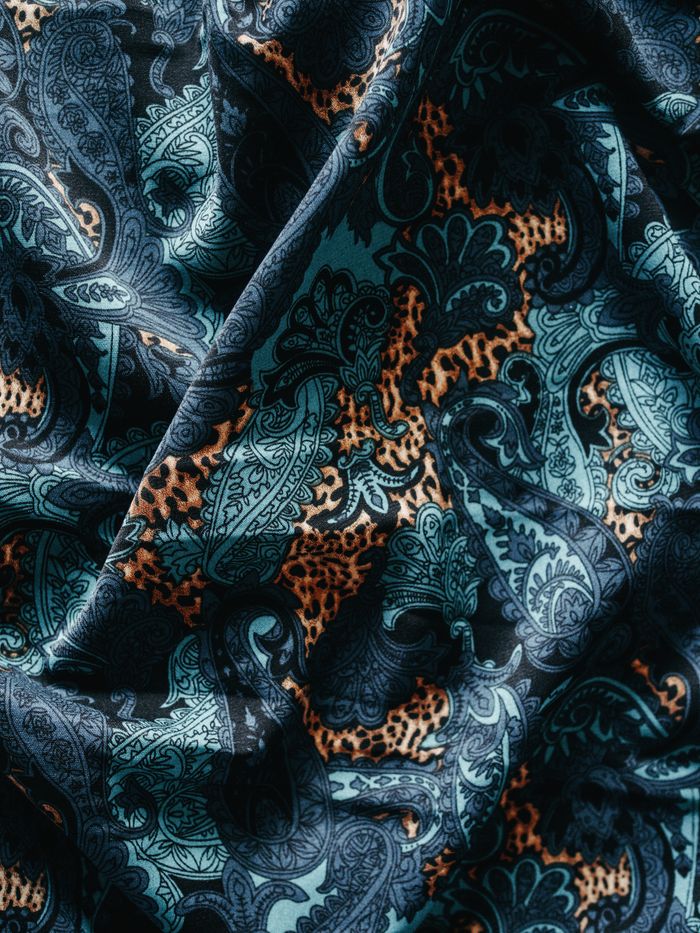 Close-up of a colorful paisley fabric with intricate patterns and bold textures.